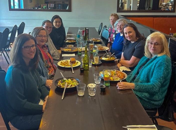 A group of people sit at a long table in a cafe.